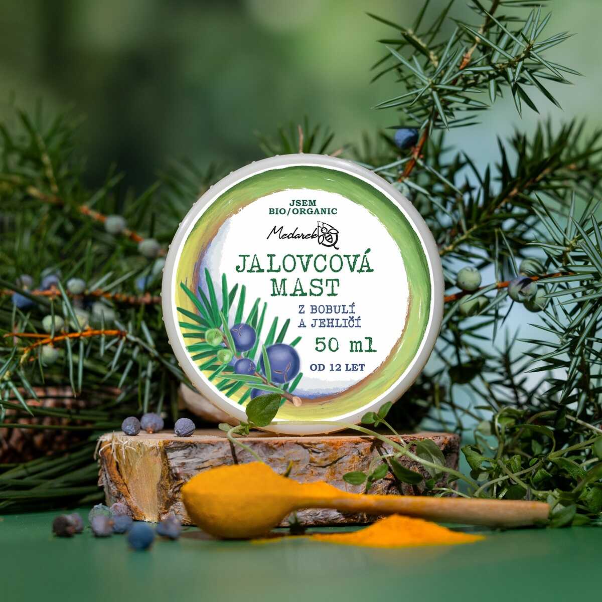 Medarek Juniper Ointment (50 ml) tin with juniper branches and berries, beside a wooden spoon of yellow powder.